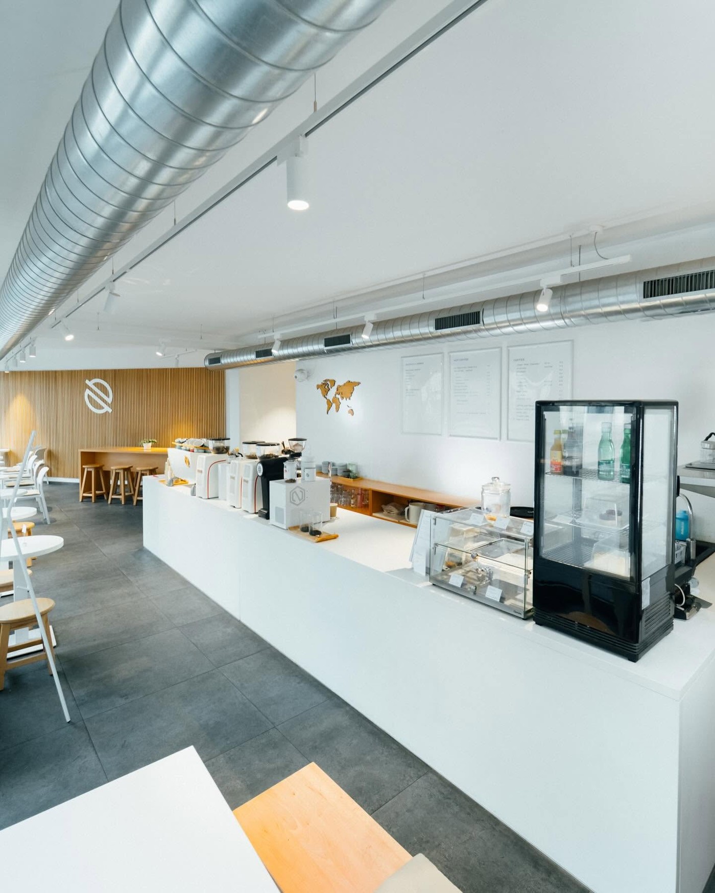 The white counter at Blend Coffee Roasters lined with espresso machines and grinders, with menu boards and a world map on the wall behind