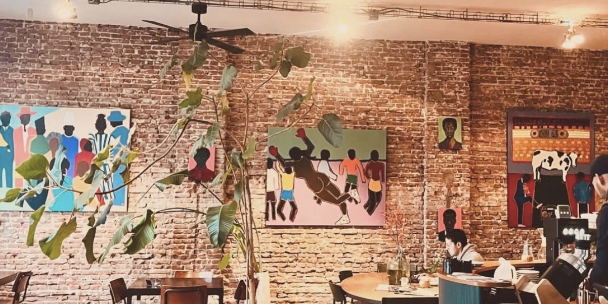 The brick walled dining room hung with colorful figurative paintings, a fig tree beside the counter