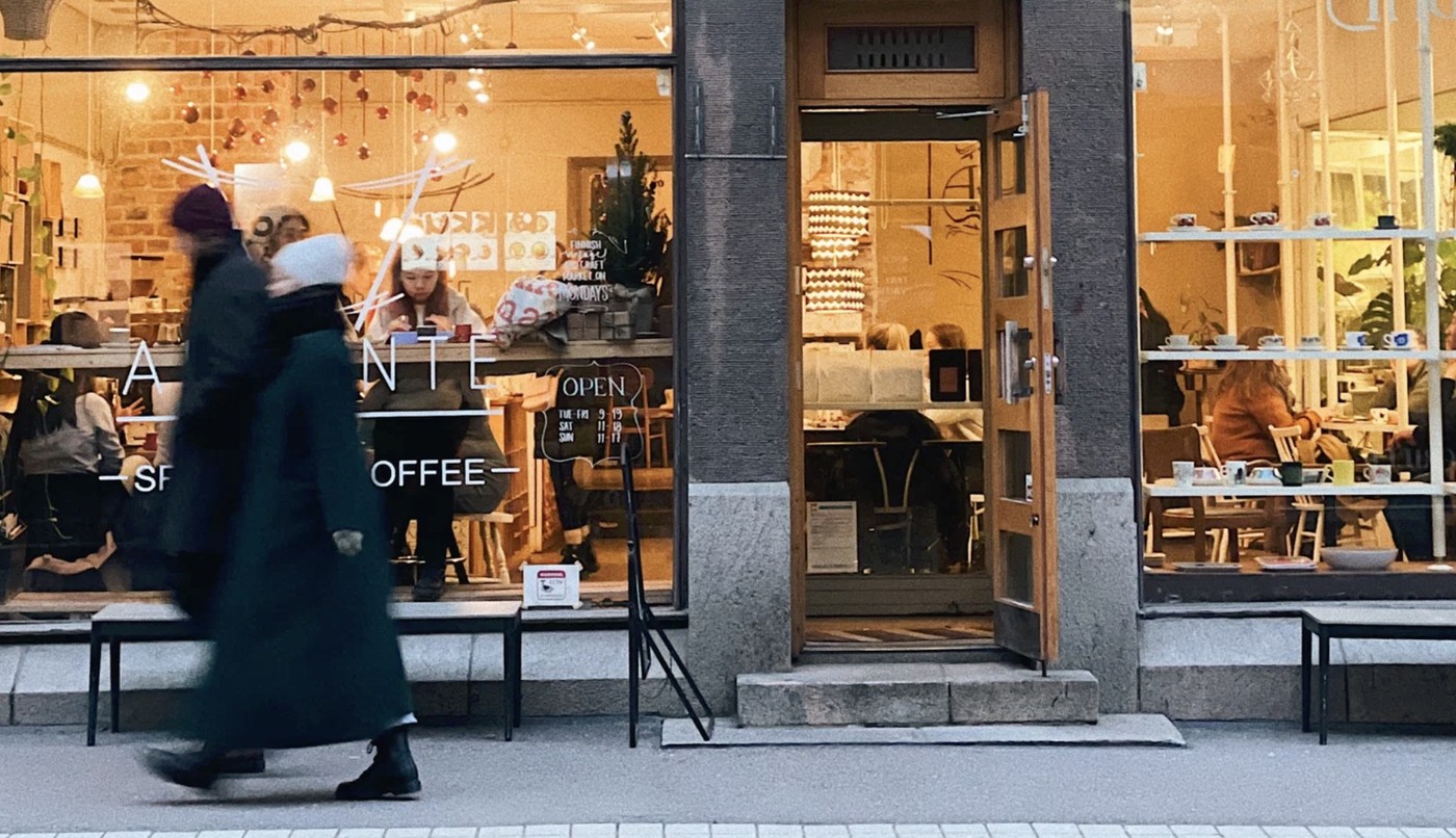The storefront of Andante Specialty Coffee at dusk with an open door and people seated inside