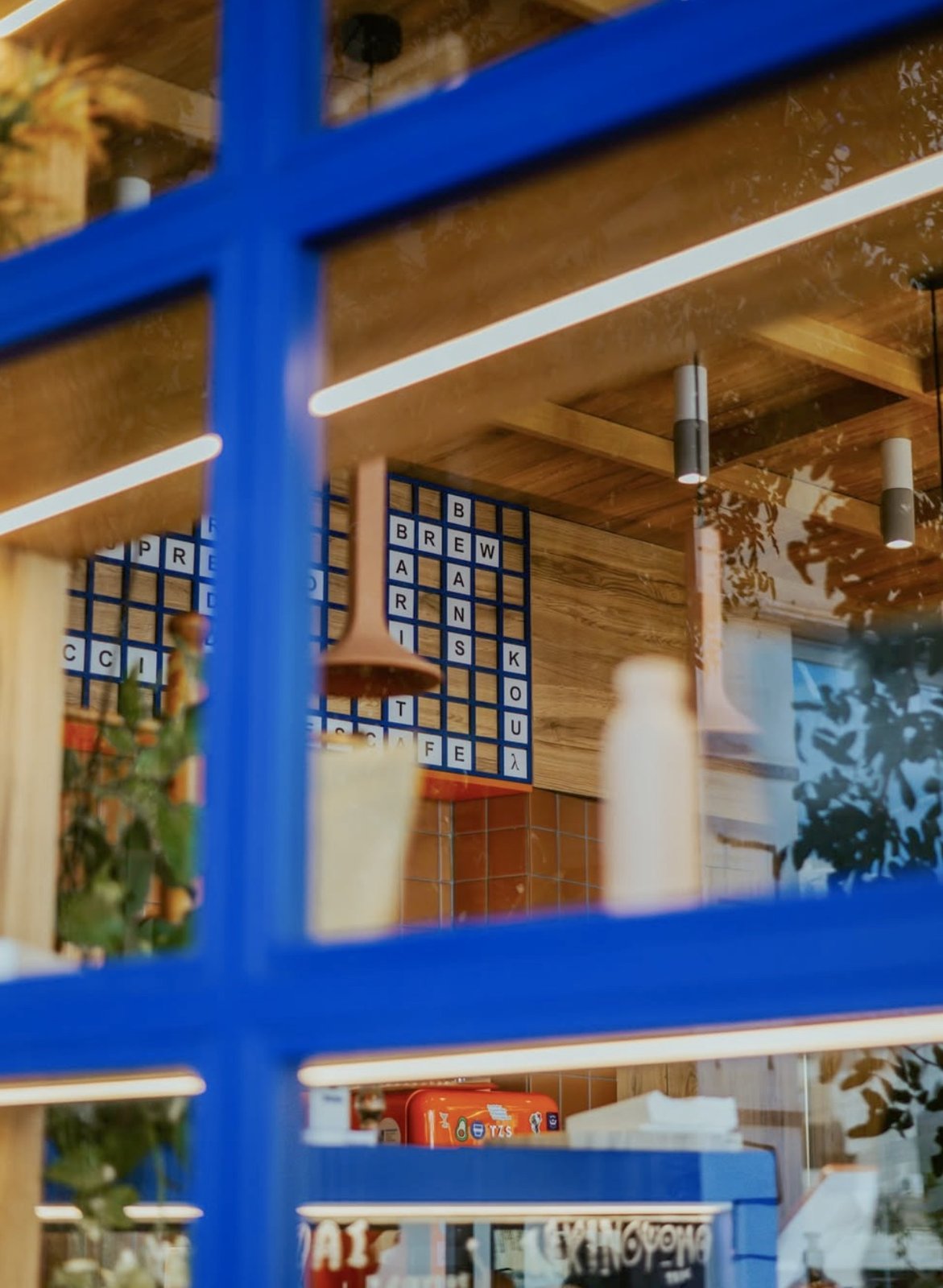 The window at Koul Microbakery with its letter tile sign spelling out Brew Barista Koul Coffee, seen through blue framed panes