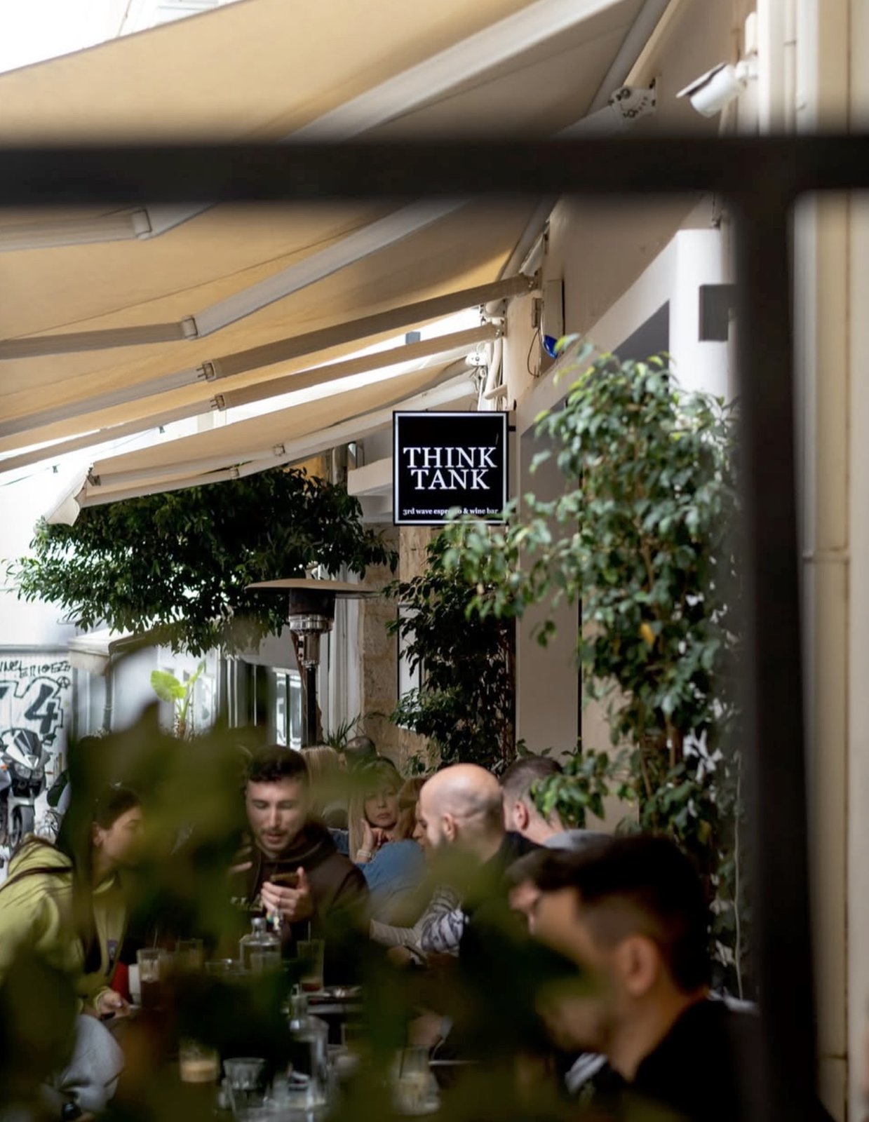 The Think Tank sign hangs over the shaded terrace, with customers seated at outdoor tables under the awning