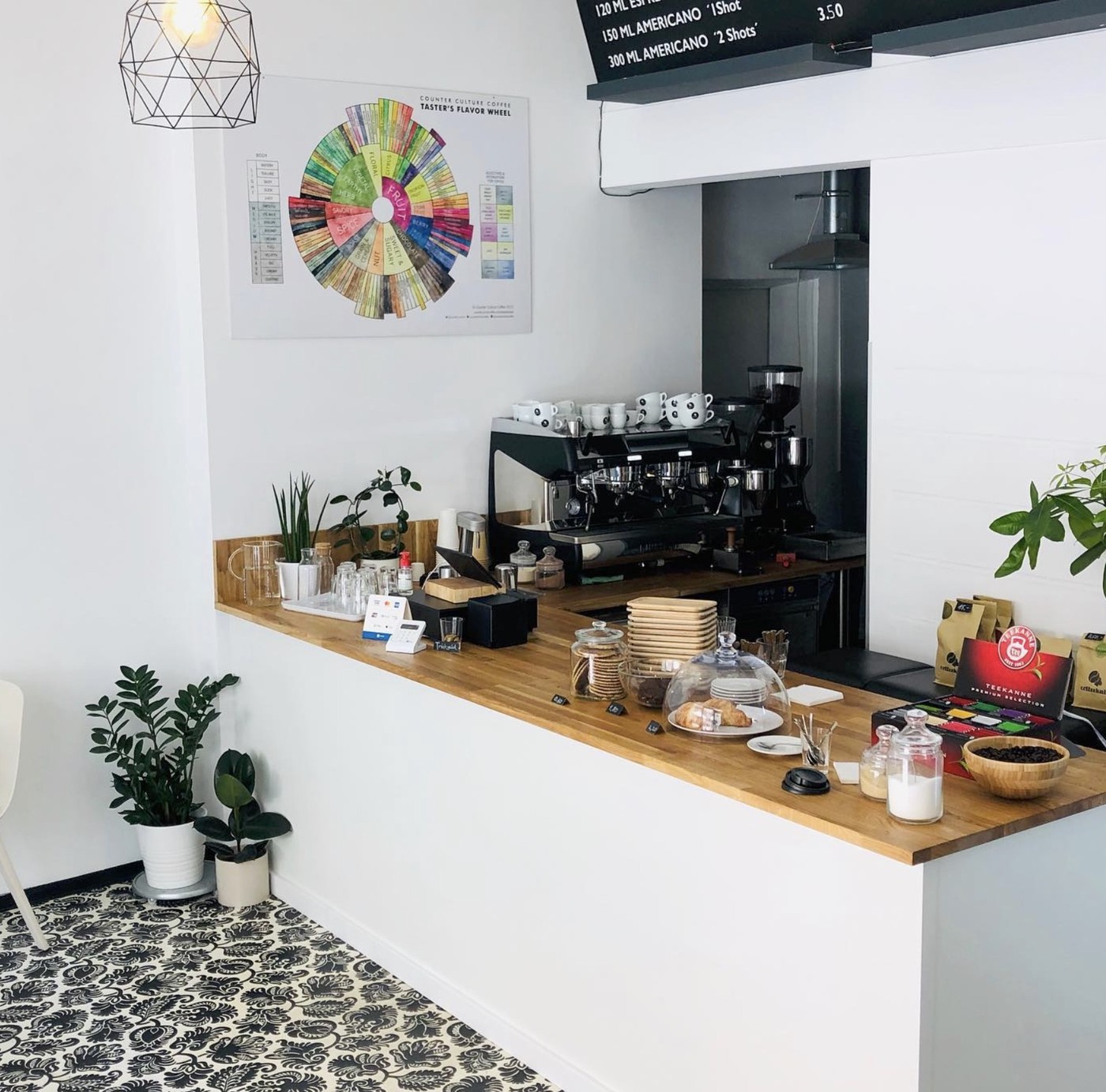 The Coffeelab espresso counter with a Counter Culture flavor wheel poster, retail bags, and a pastry case beneath the menu board