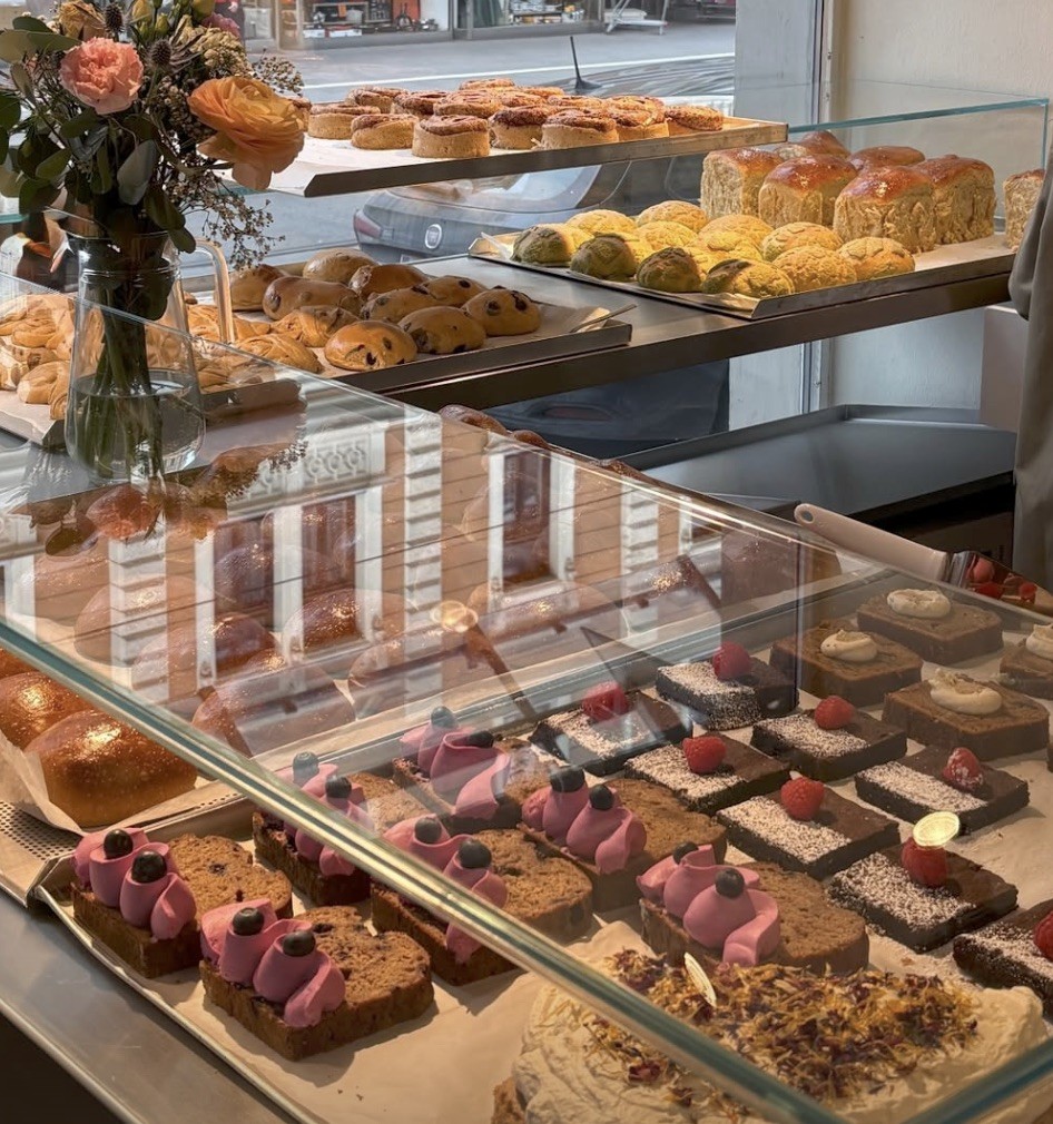 The pastry and bread display case at Kula.Lab's open sourdough bakery, filled with cakes, brioche, and fresh loaves