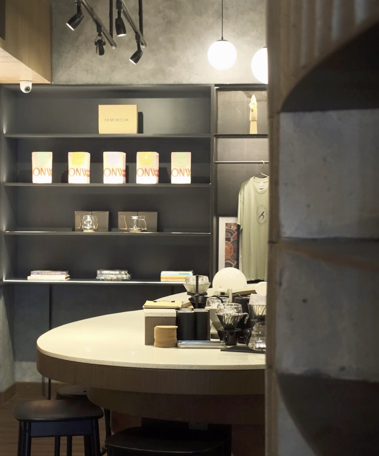 The retail wall behind the pour over bar, stocked with Onward branded coffee bags, glassware, books, and a hanging t shirt