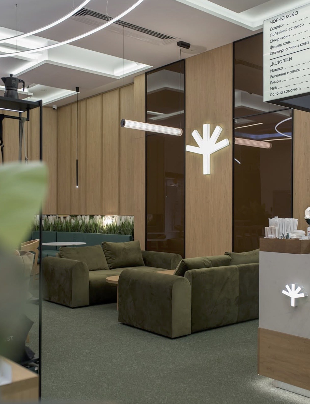 A green velvet lounge seating area at Idealist Coffee, wood paneled walls and a white branch shaped light fixture