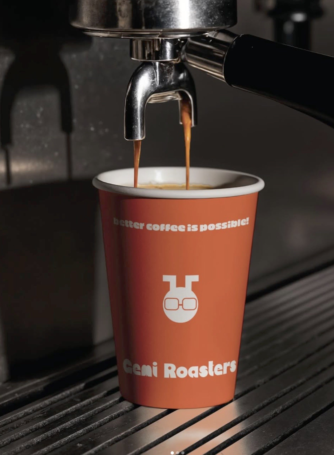 Espresso pouring from a portafilter into a branded orange Gemi Roasters cup reading Better coffee is possible
