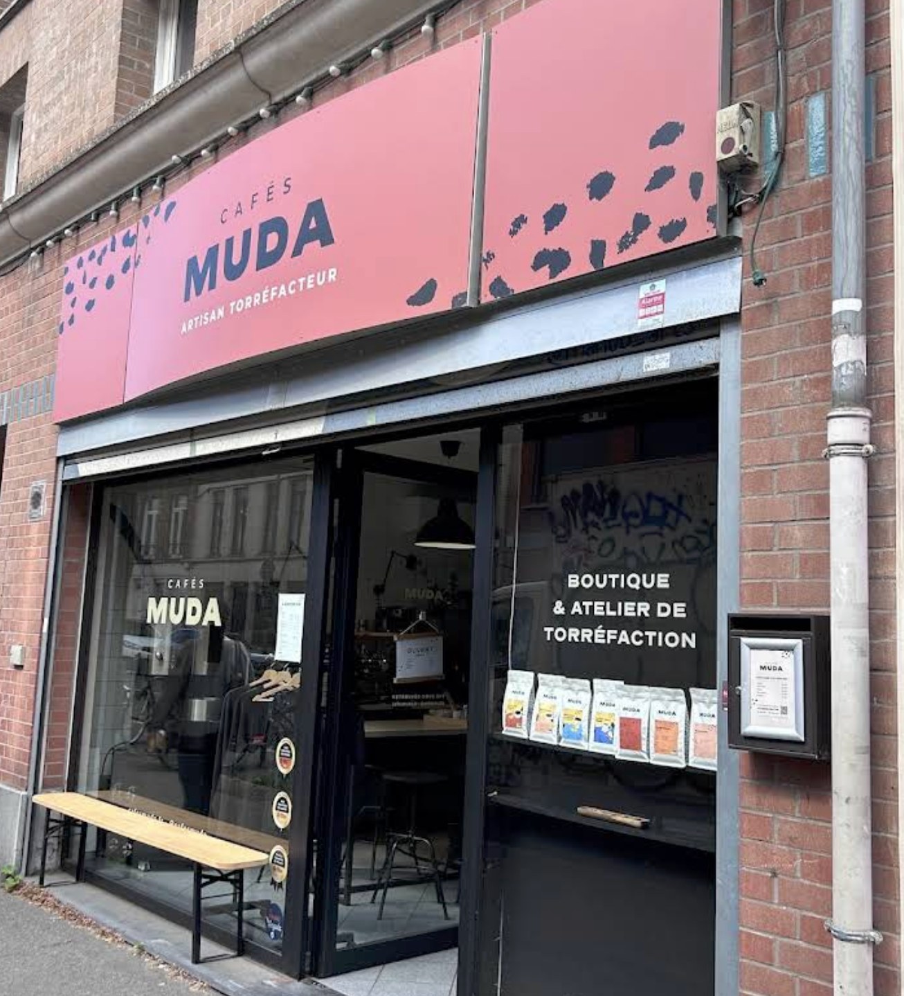 The storefront and pink signage at Cafés Muda on rue d'Arras