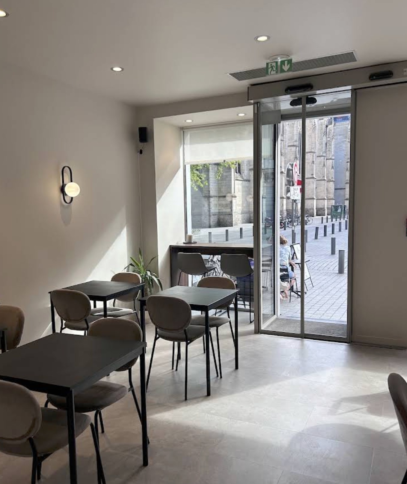 The bright, minimalist dining room at Mü Café, with a view across the terrace to Saint Maurice church