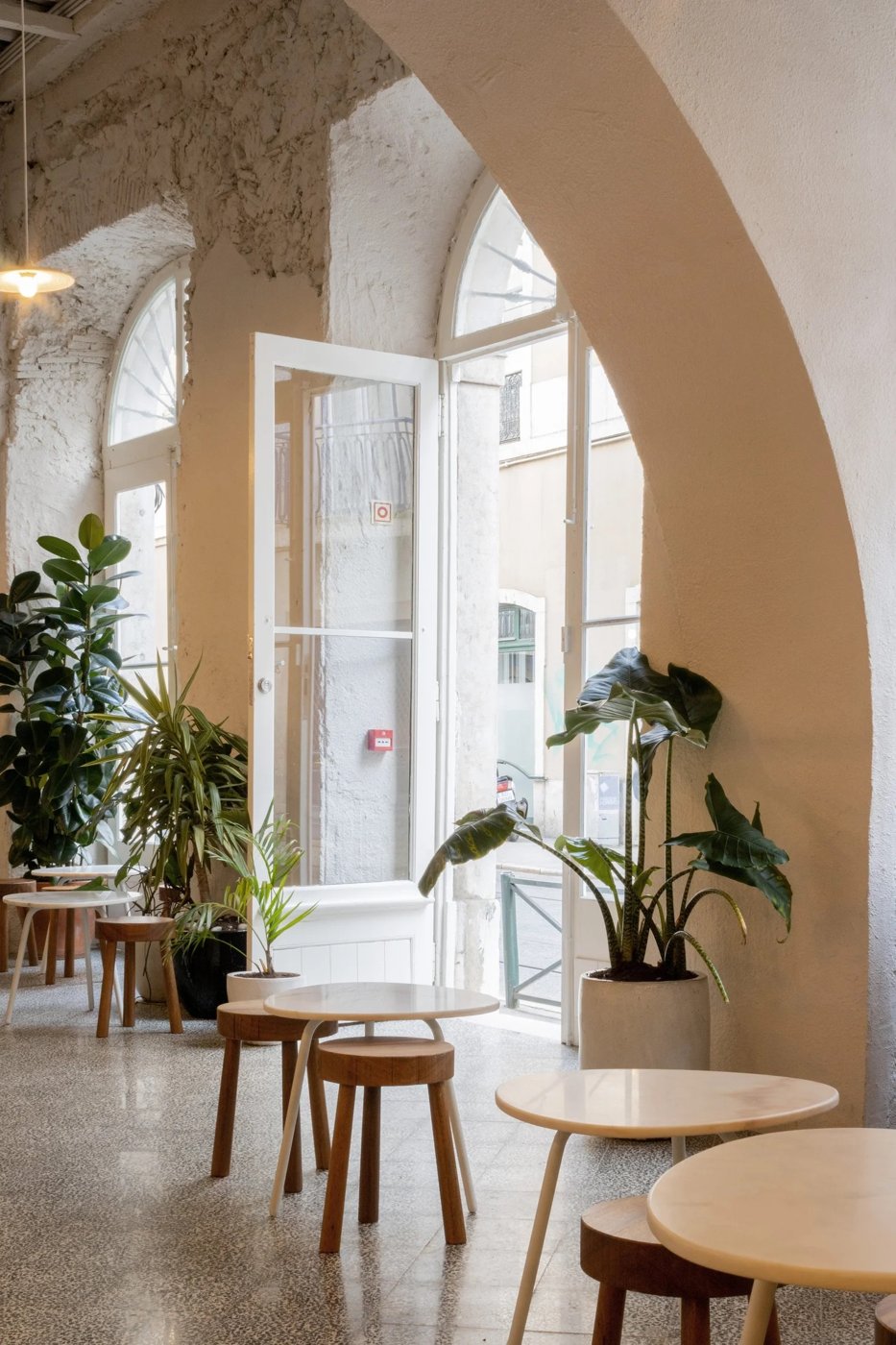 The whitewashed arched interior of Comoba, small marble tables and potted plants beneath the arches