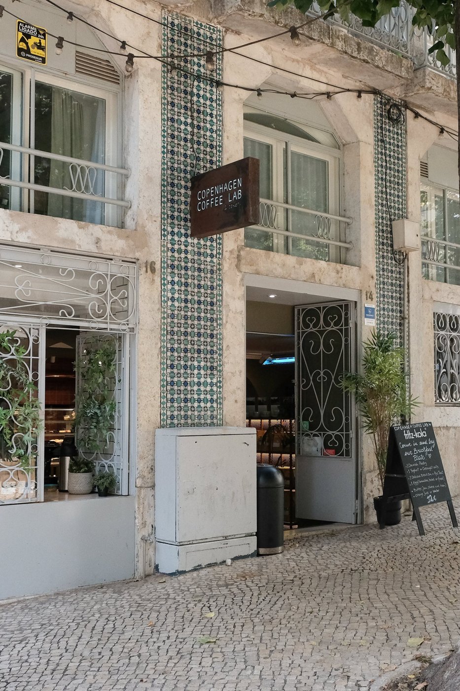 The azulejo-tiled facade of Copenhagen Coffee Lab, hanging sign above the open door