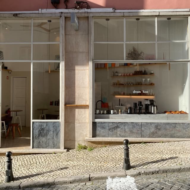 The pink storefront of Dramatico, floor-to-ceiling windows showing the counter and shelving inside