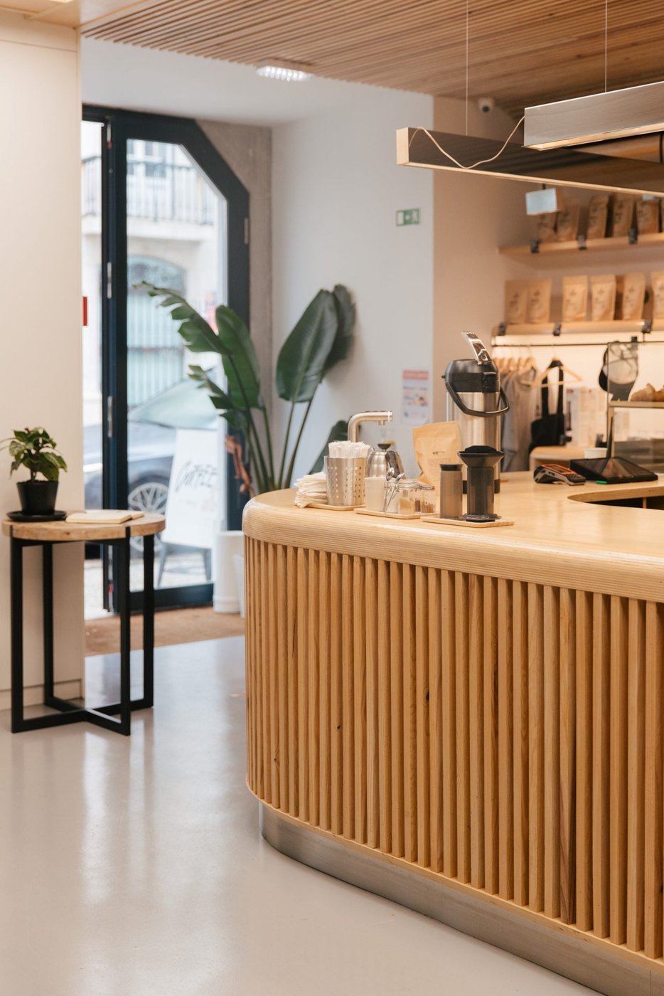 The fluted-wood counter at Fabrica Coffee Roasters, pour-over gear and bagged beans on the shelf behind