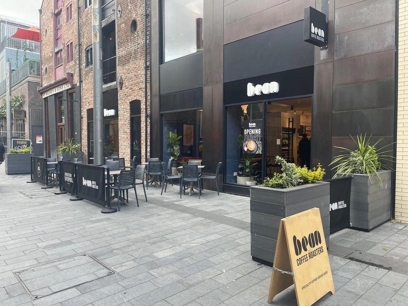The black storefront of Bean Coffee Roasters with a sandwich board and outdoor seating on a cobbled Liverpool street