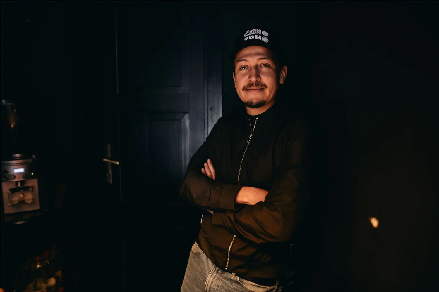 Owner Alexander Nino Ruiz standing in the doorway of Crno Zrno wearing the shop's own branded cap
