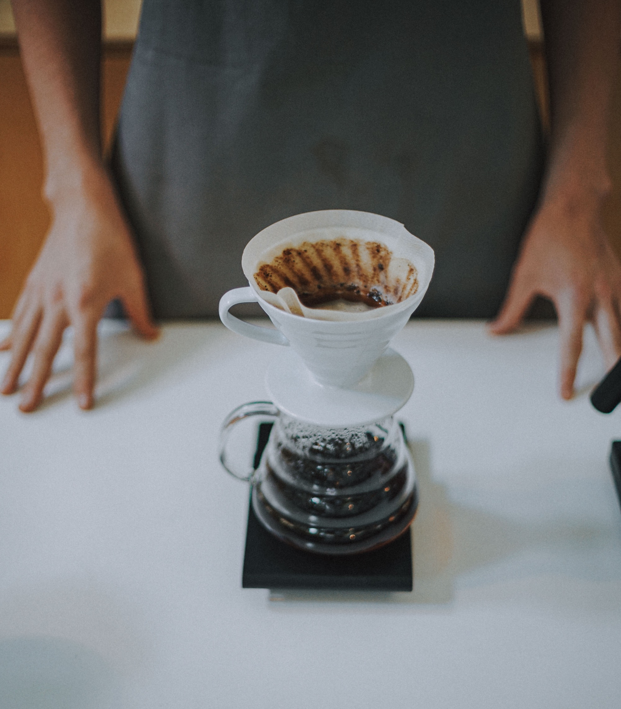 A V60 pour over dripping into a glass carafe on a white counter at Moderna in Ljubljana