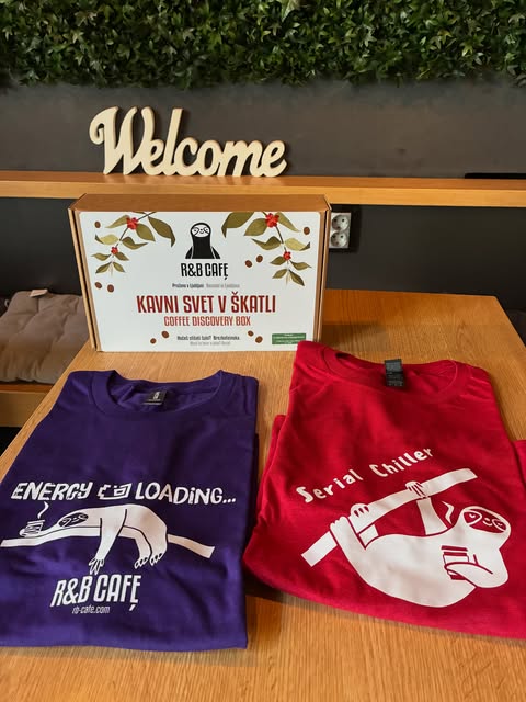 A Welcome sign and R&B Cafe branded coffee box and t-shirts arranged on a table inside the shop