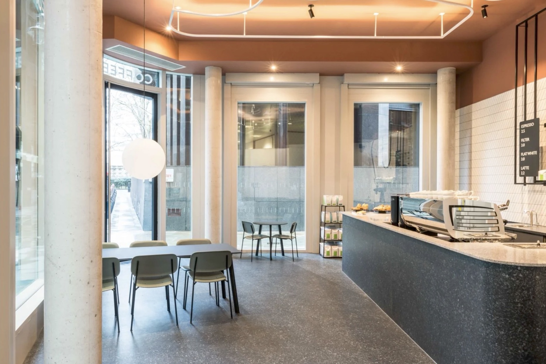 The interior of Formative Coffee, a terracotta ceiling, marble counter, and window seating along the corner site