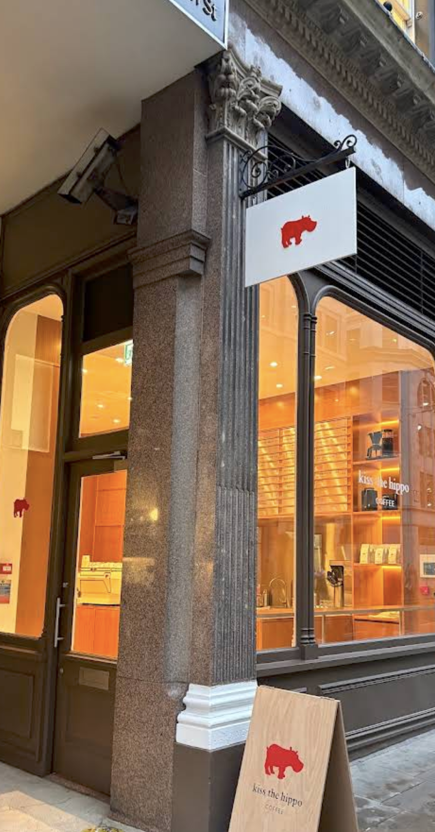 The Kiss the Hippo storefront on Cannon Street, red hippo logo signage above the corner entrance and warm light through the windows