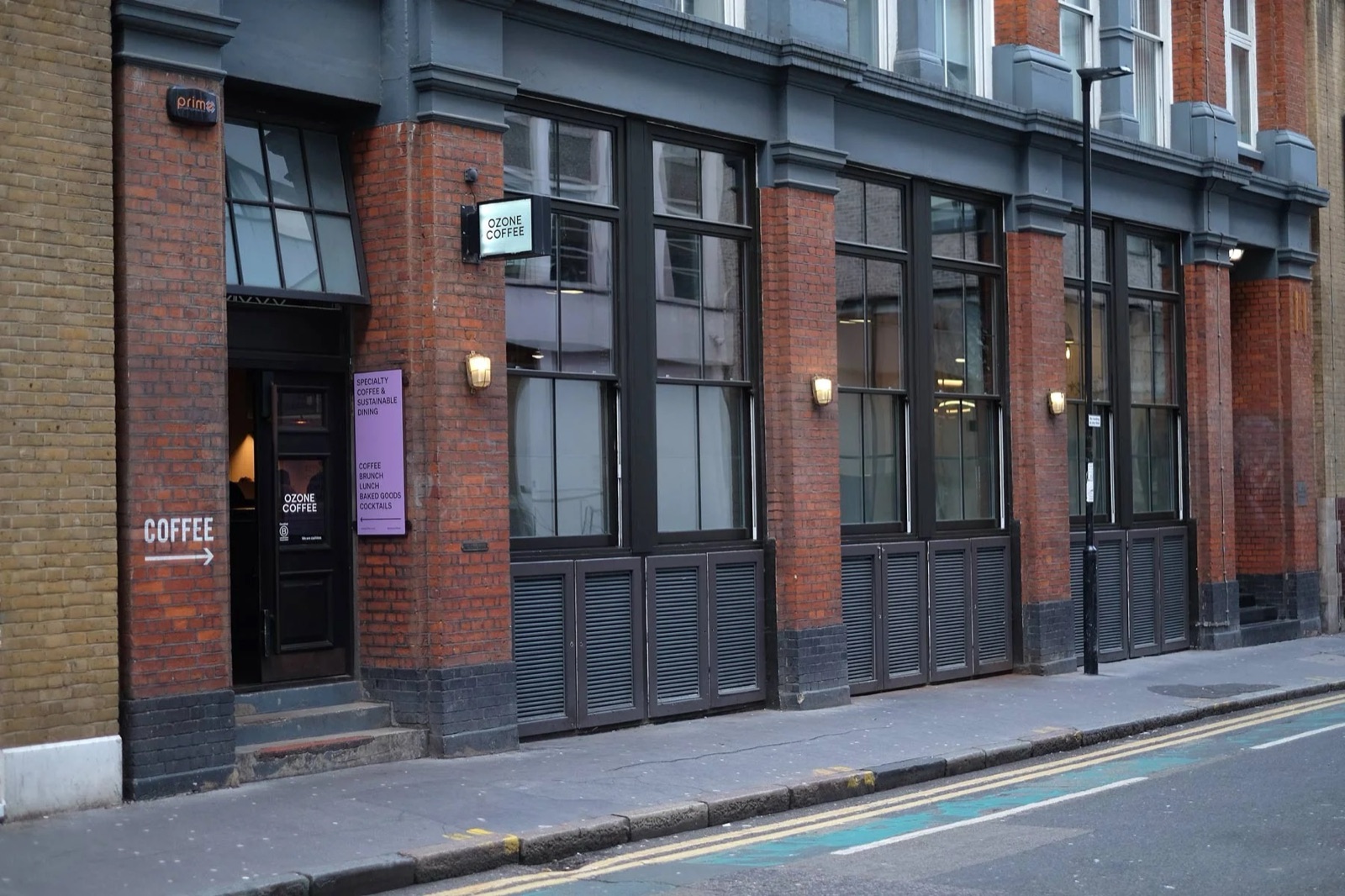 The red-brick Ozone Coffee storefront on Leonard Street, a purple 'Specialty Coffee & Sustainable Dining' sign by the entrance