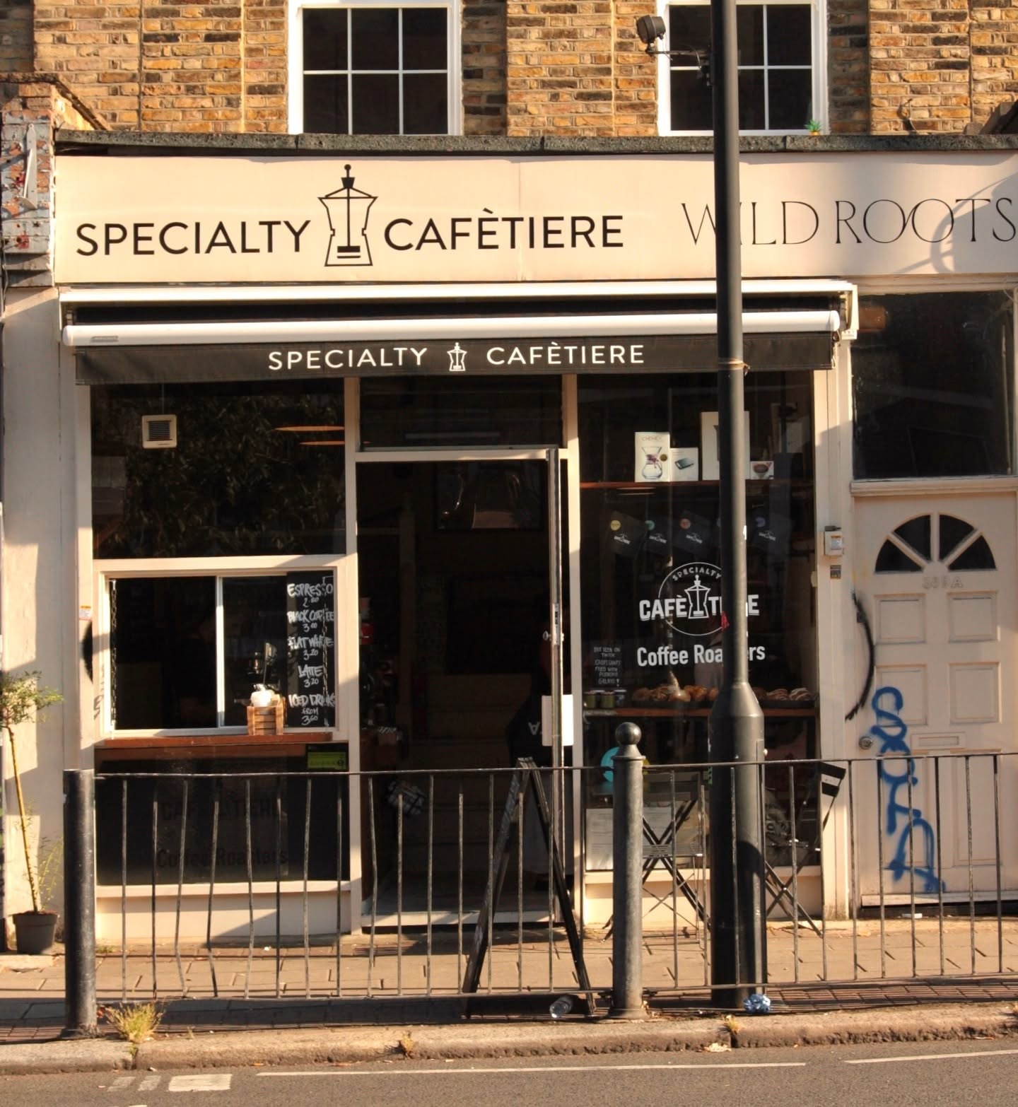 The cream and black Specialty Cafètiere storefront with the shop's coffee pot logo on the awning sign