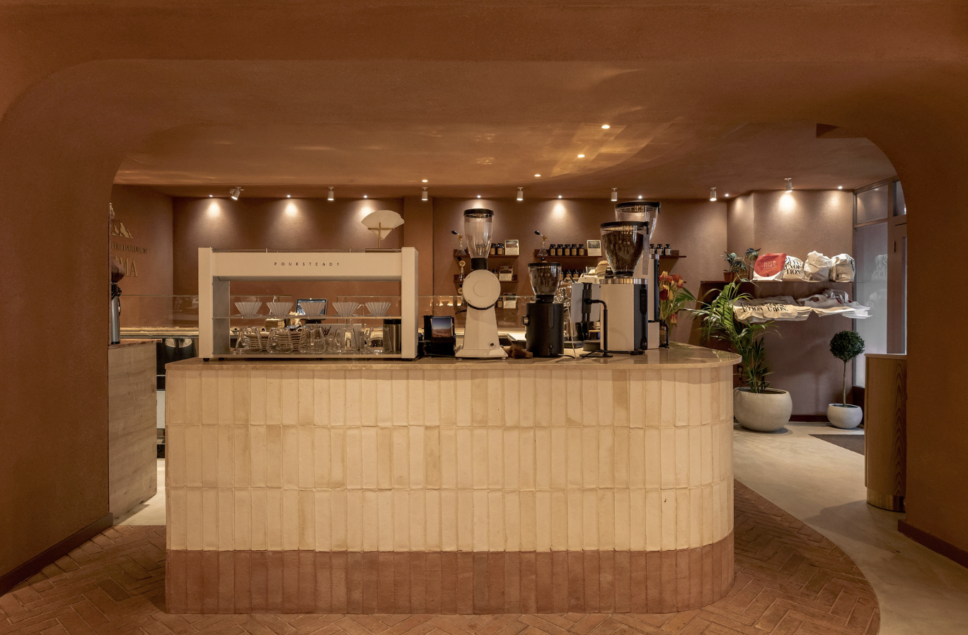 The curved terracotta tiled bar at Qima Cafe, batch brewers and grinders on the counter under warm lighting