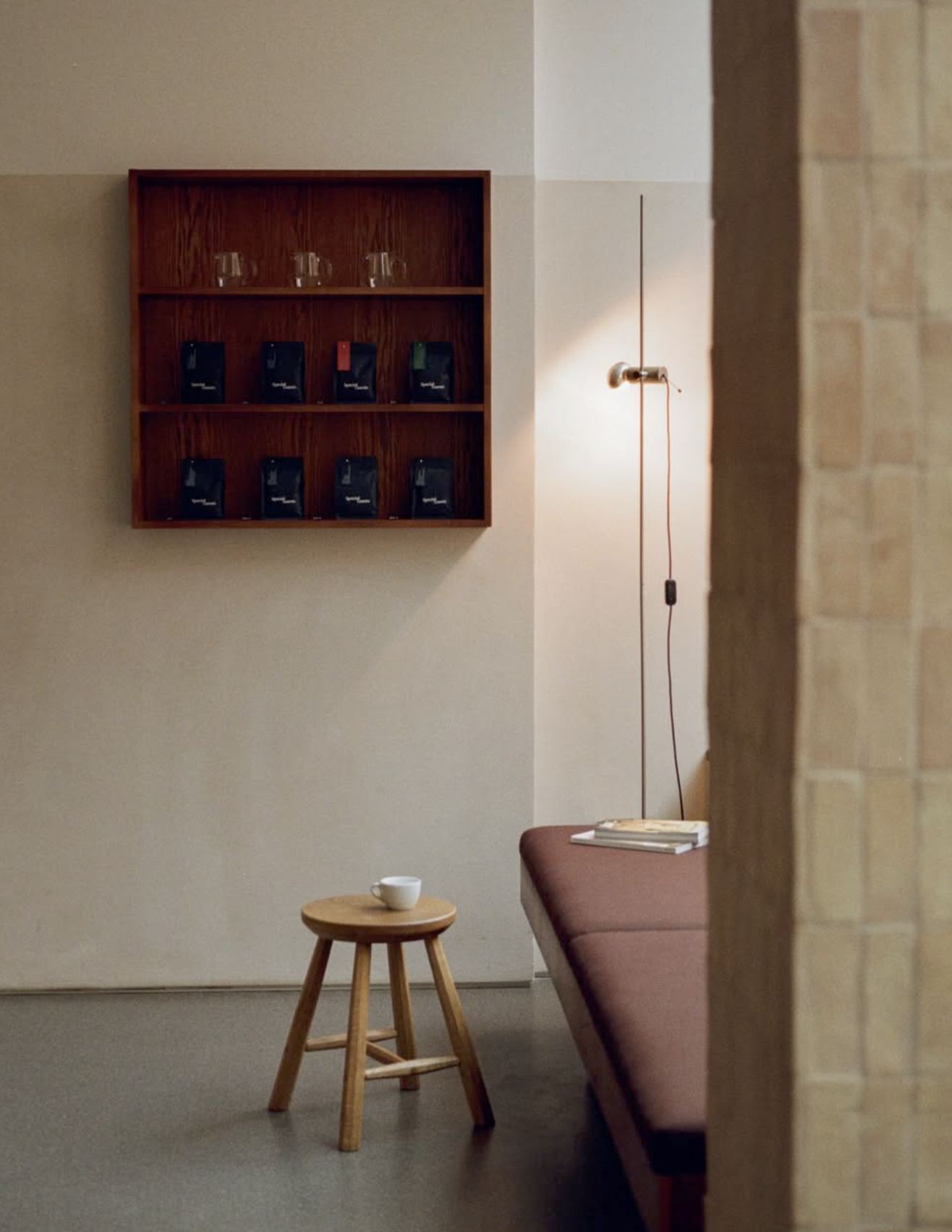 A wall shelf of Special Guests retail bean bags above a stool and terracotta tiled corner at Special Guests