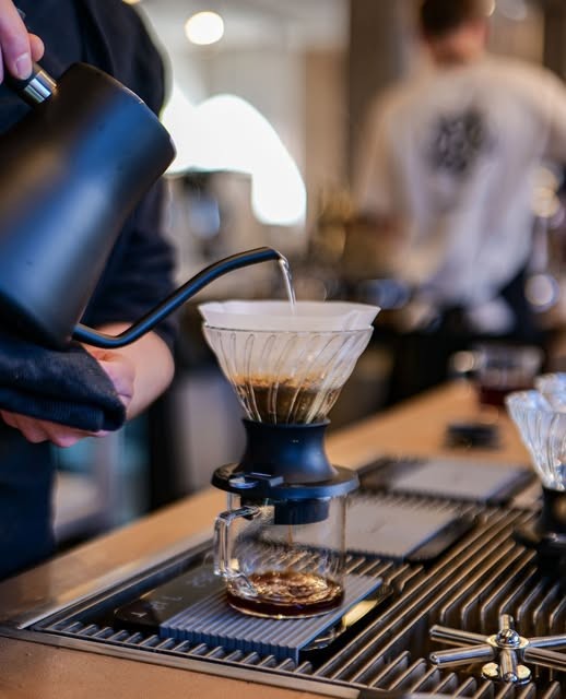 A hand pouring water over a V60 pourover cone on the counter at Mokxa