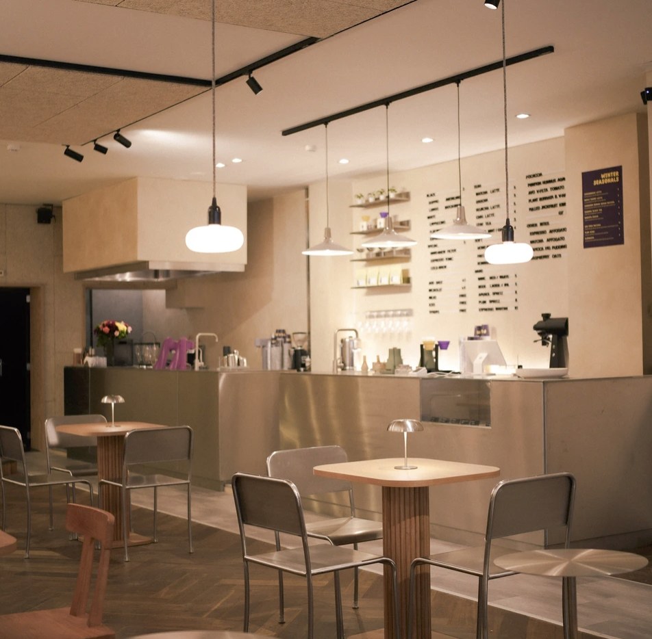 The dining room at PLUM Specialty Coffee, with pendant lighting over small tables