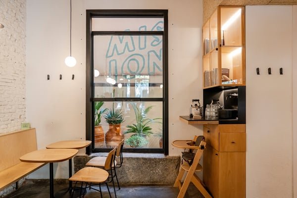 The window seating at Mision Cafe, MISION lettering on the glass and potted plants in the light well
