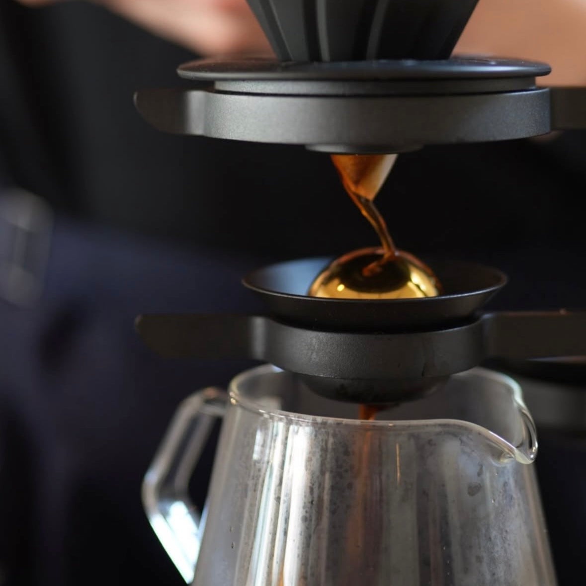 Coffee streaming from a pour over dripper into a glass carafe on Nordic Brew Lab's brew bar
