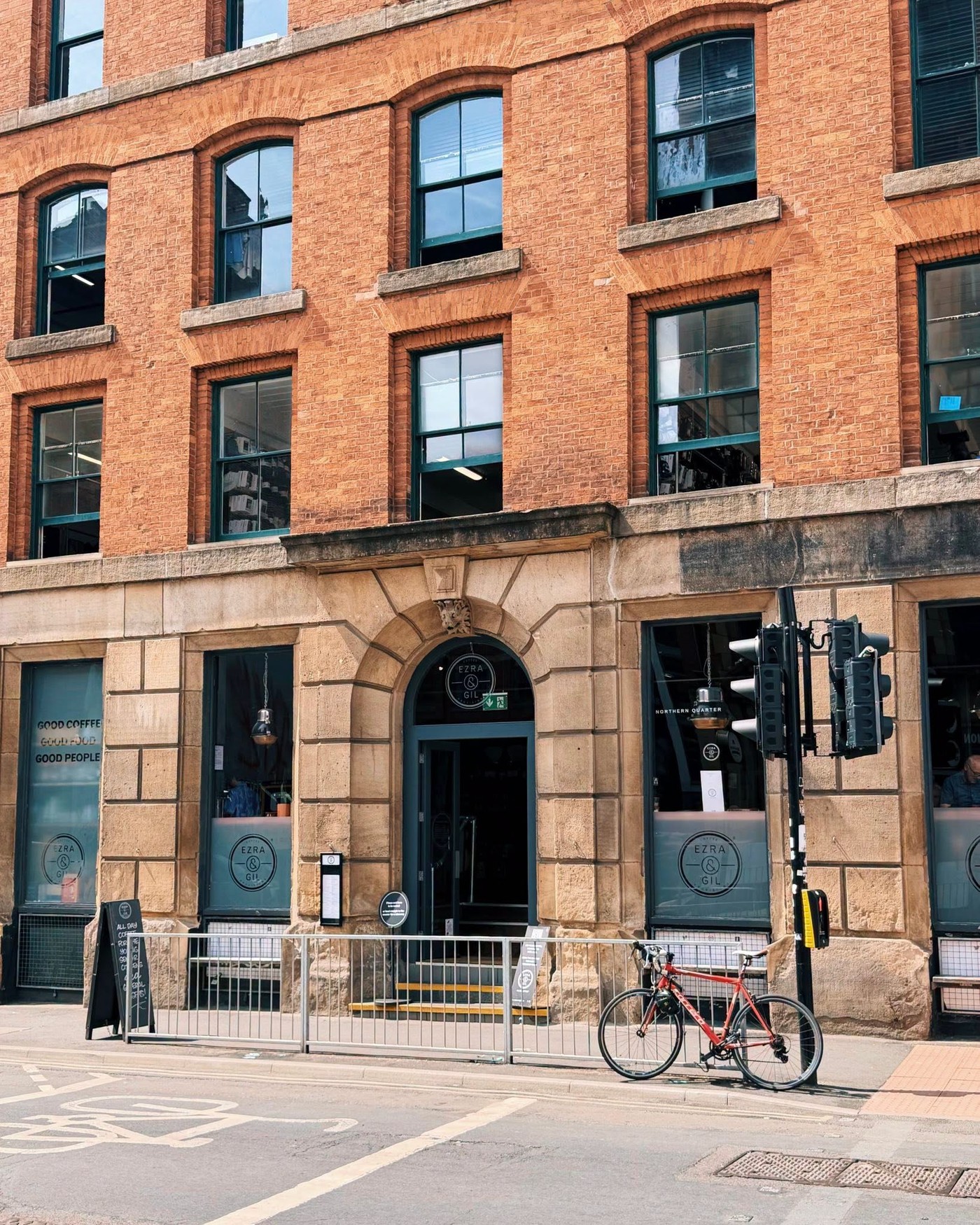 The red brick exterior of Ezra & Gil on Hilton Street with the round logo etched on the windows and a bicycle parked outside