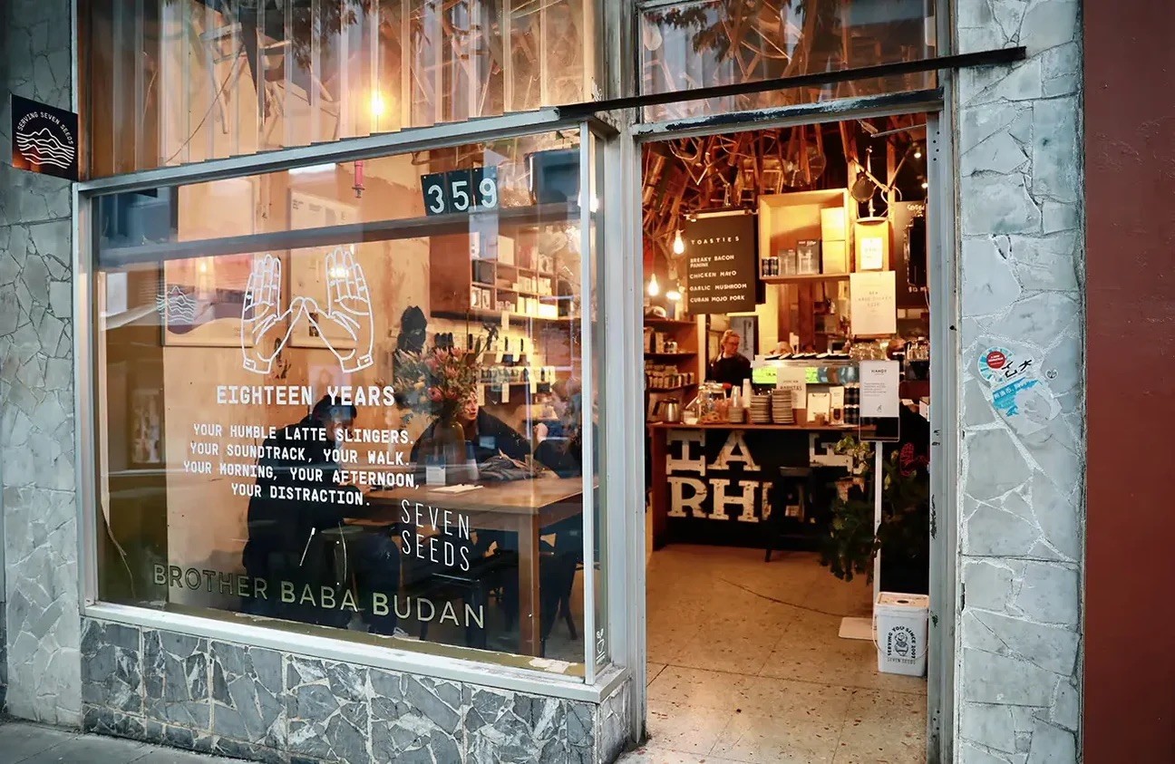 The Brother Baba Budan window reading Eighteen Years and Seven Seeds, with a barista working the counter through the open doorway