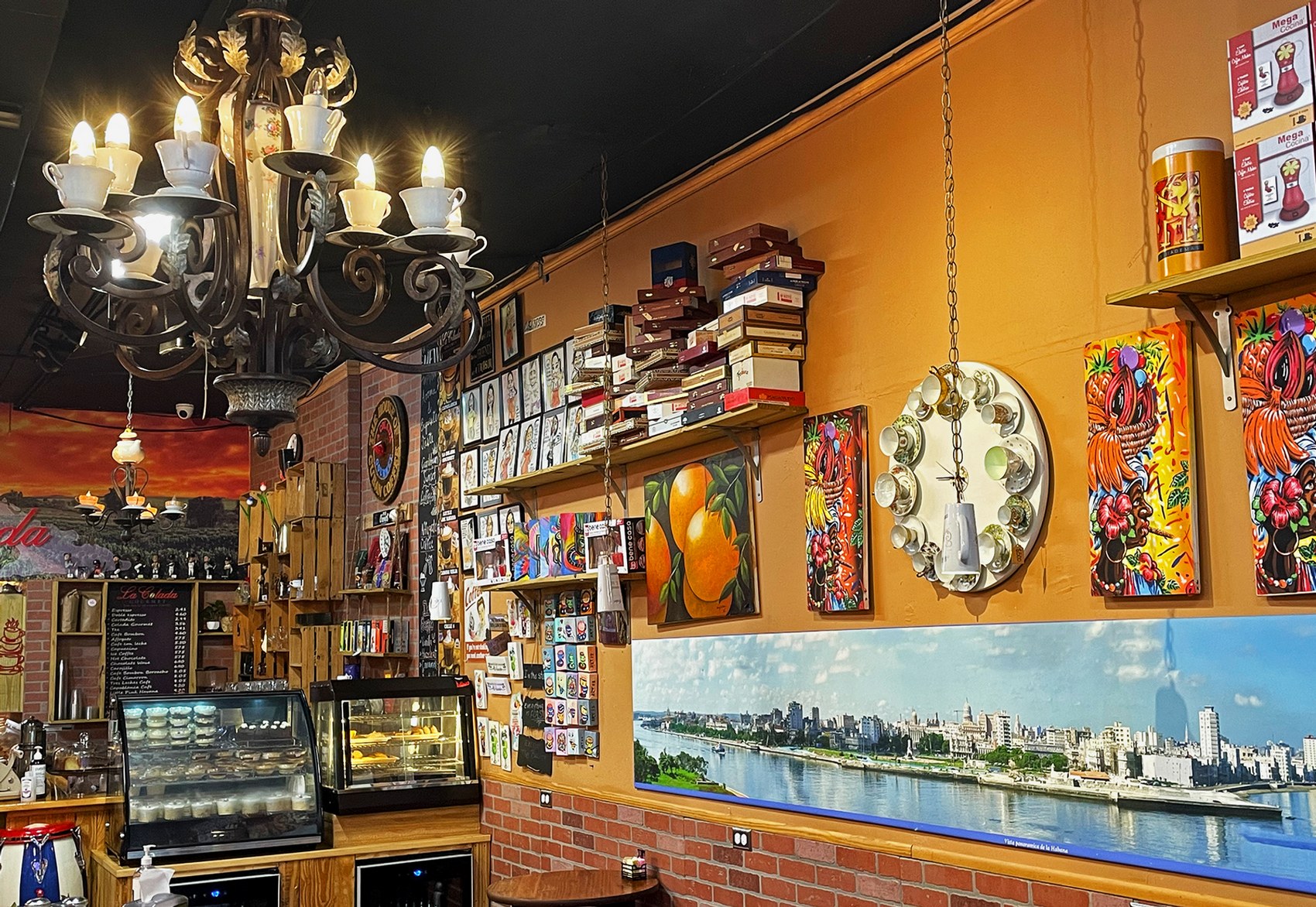 The interior wall at La Colada Gourmet lined with cigar boxes, local art and a Havana skyline panorama