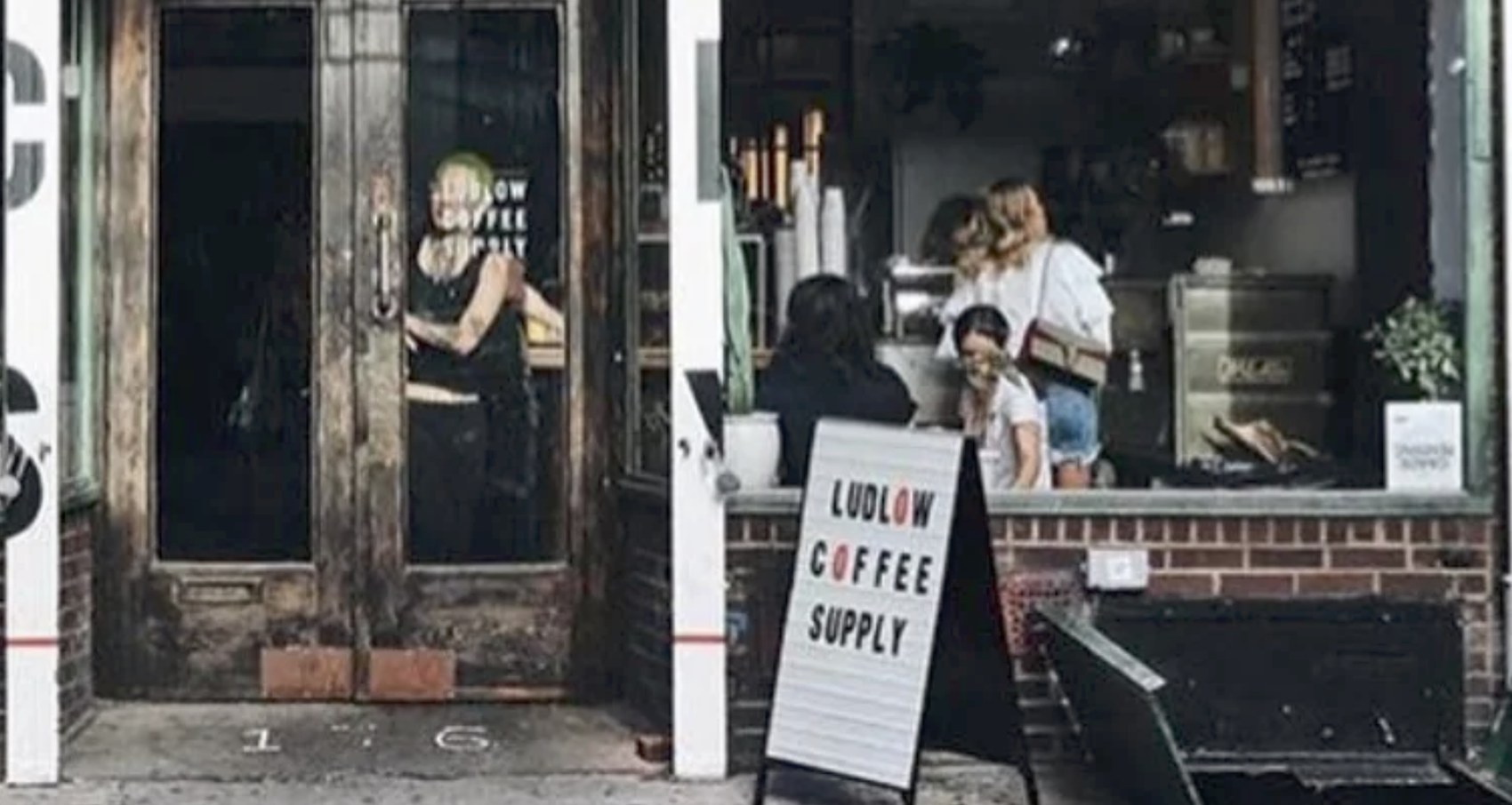The storefront entrance and counter at Ludlow Coffee Supply with the sandwich board sign out front