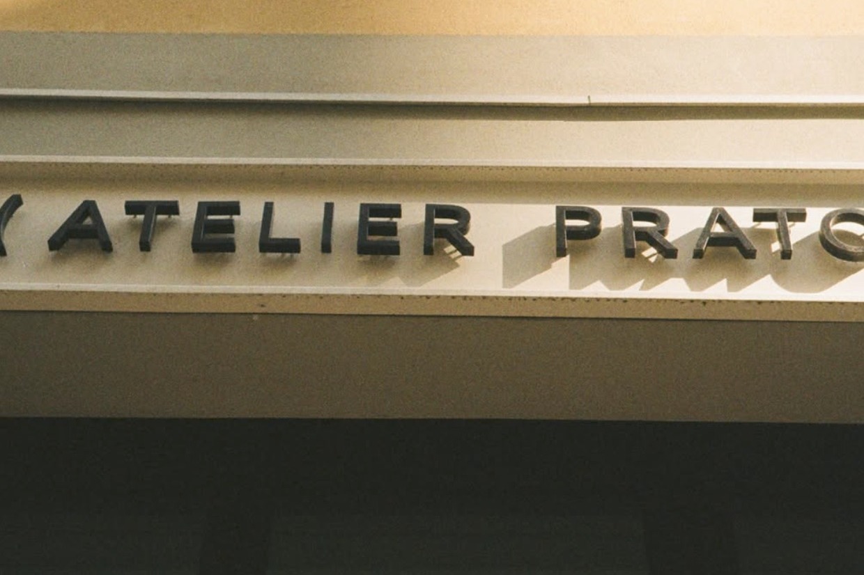 The ATELIER PRATO sign in black lettering above the entrance, lit by warm evening light