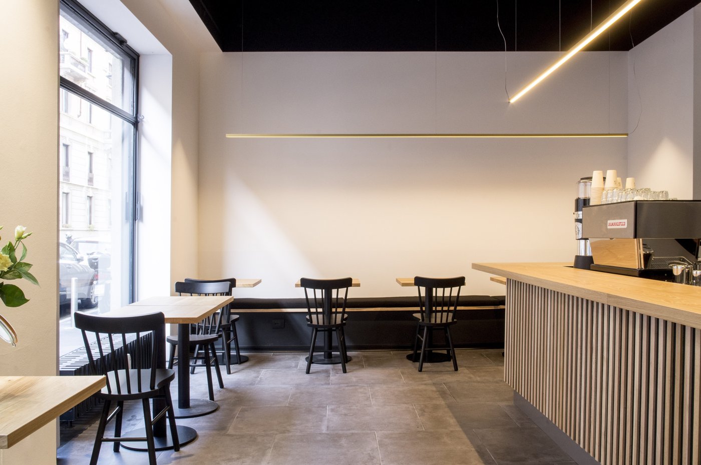 The minimalist dining area at Loste Cafe, black chairs and a wood-slatted counter