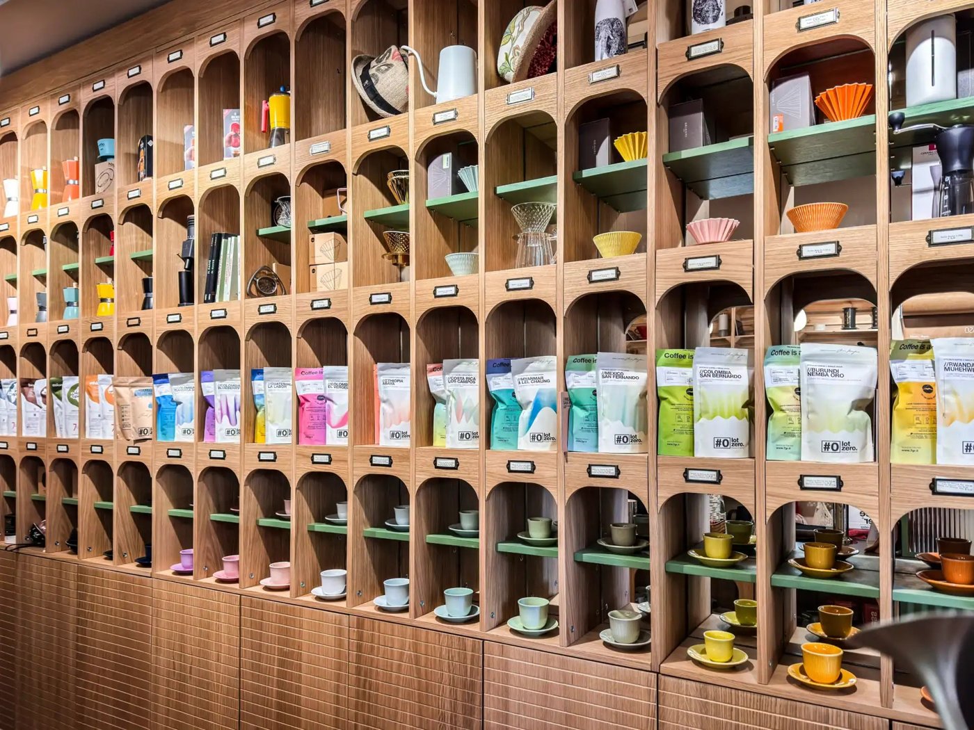 The arched wooden shelving wall at Sevengrams Coffee Studio, displaying bagged coffee and cups