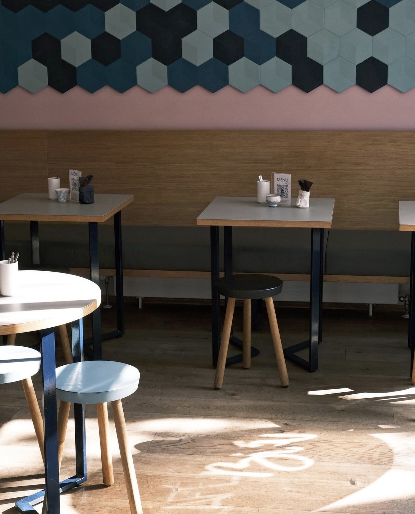 Café Blá's hexagonal tiled feature wall in dark blue and teal above a pink wall and wood-paneled booth seating