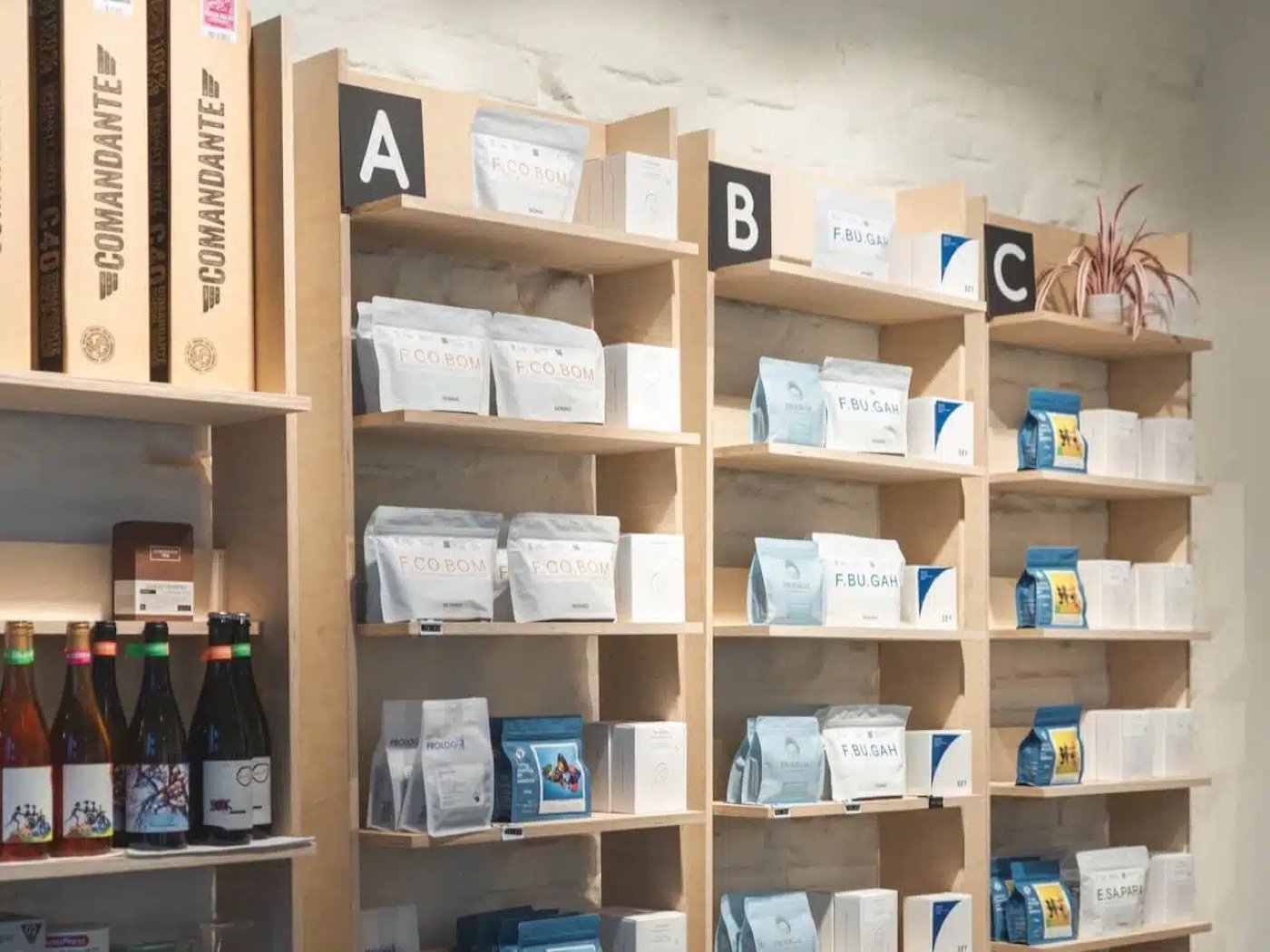 A retail wall of labeled coffee bean bags organized into lettered sections at sweet spot kaffee