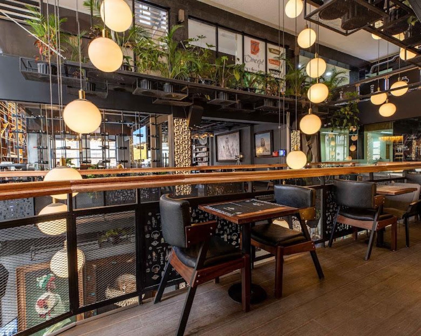 The multi-level lounge seating at Cafe Amka, globe pendant lights and hanging plants over leather chairs