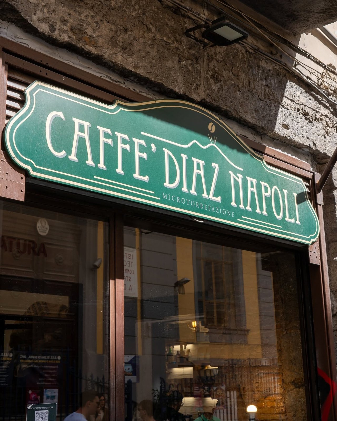 The green storefront sign reading Caffè Diaz Napoli Microtorrefazione, mounted above the shop's glass entrance on Via dei Tribunali