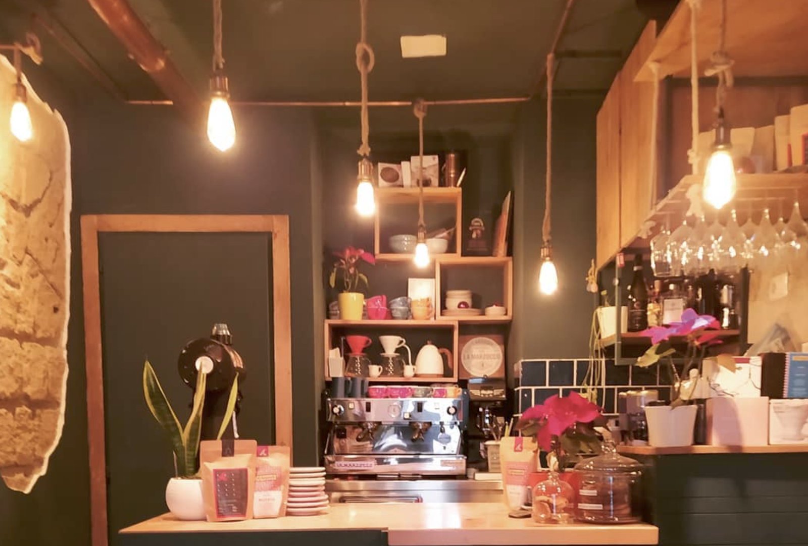 The narrow espresso bar at Ventimetriquadri, with the espresso machine, bagged beans and pour over gear lit by warm hanging bulbs