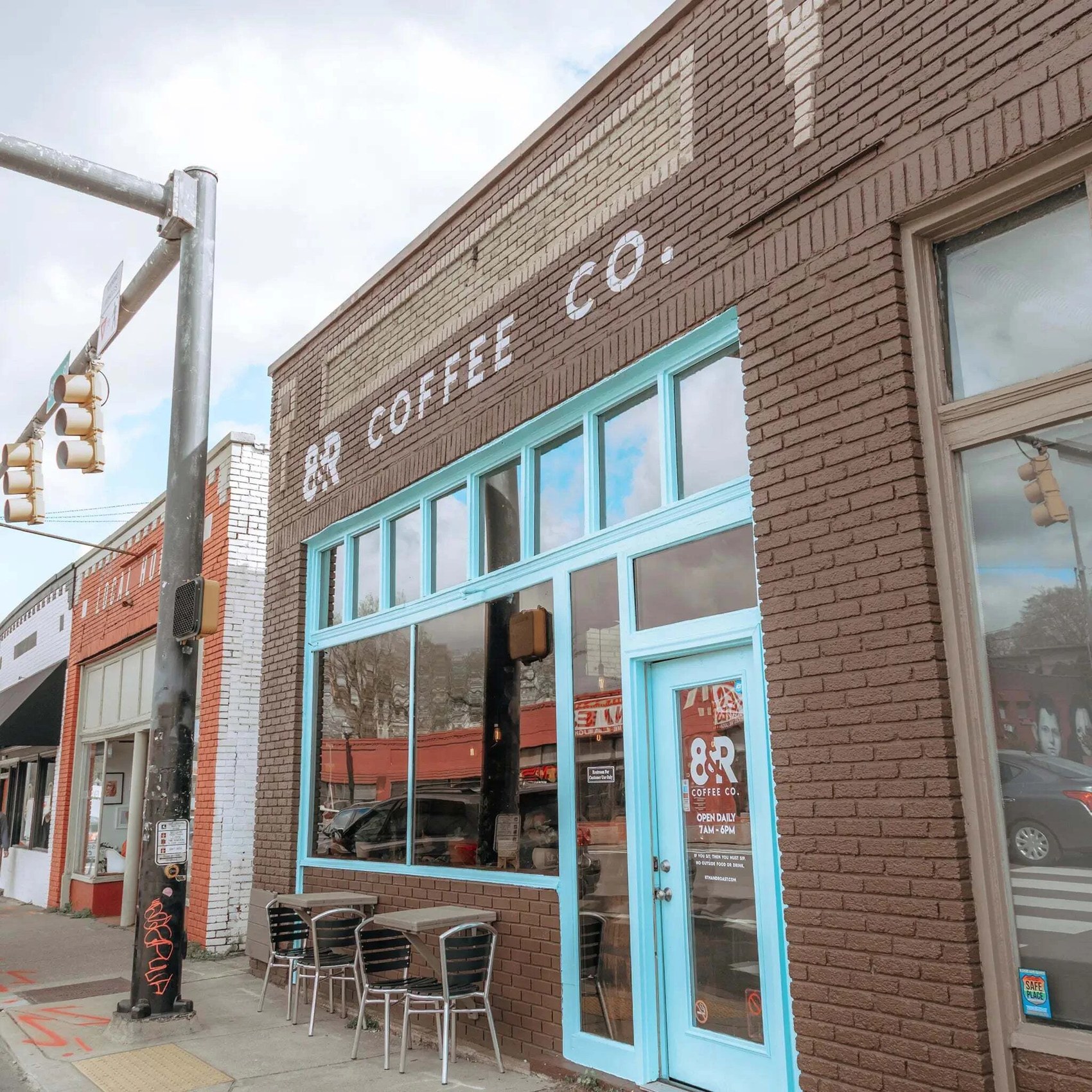 The painted brick storefront of 8th & Roast with its teal windows and door