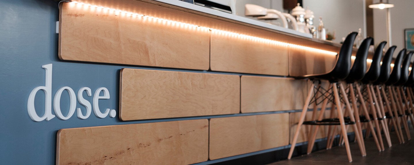 The dose. wordmark on the wall beside the illuminated wood counter