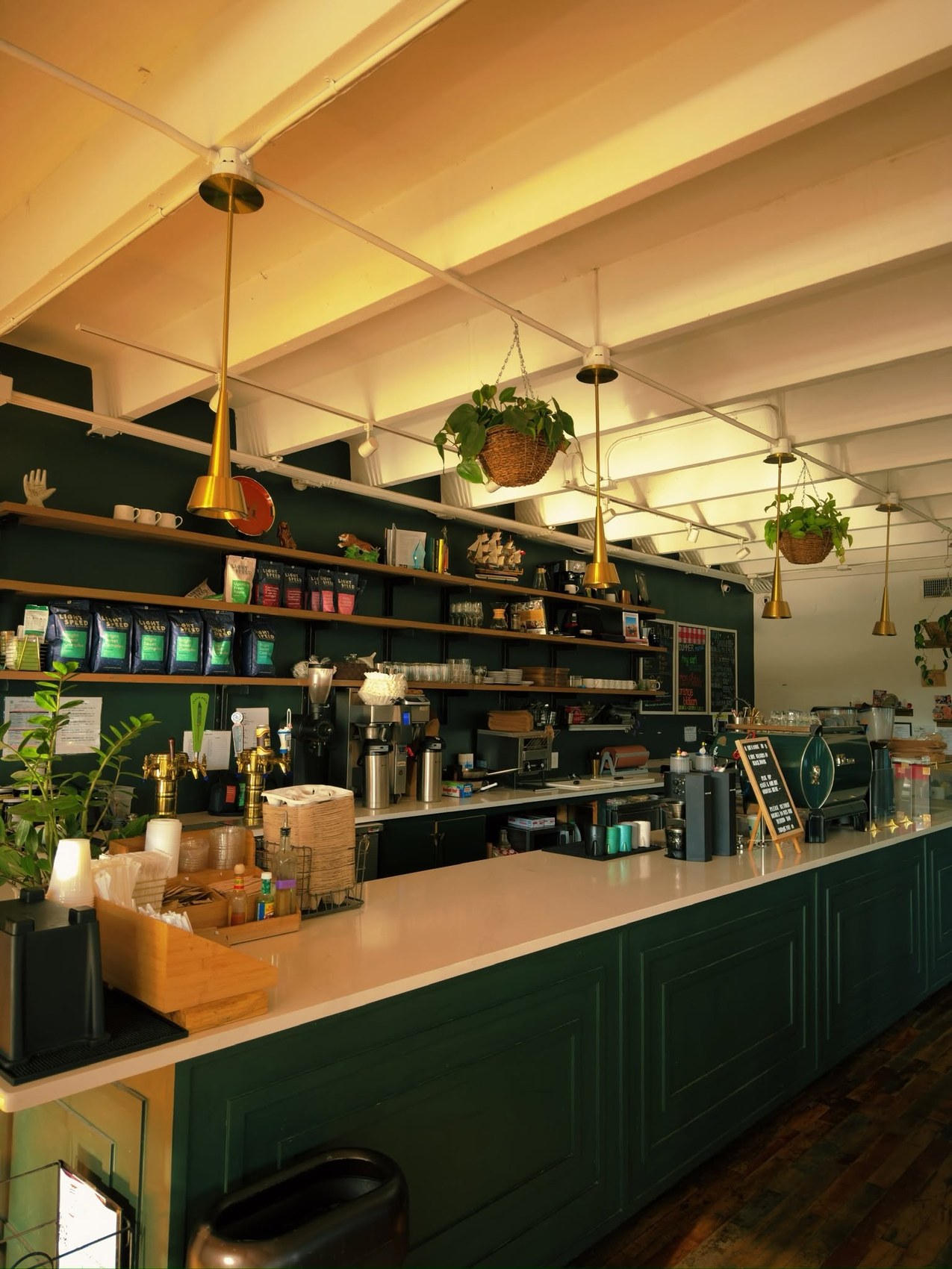 The green counter beneath shelves of branded Light Speed retail bags at Retrograde Coffee