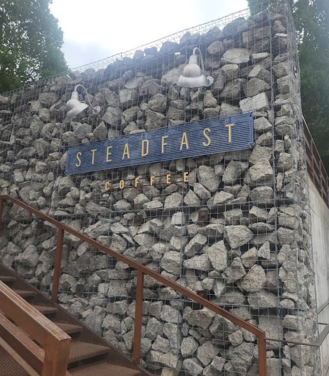 The gabion stone wall entrance with the Steadfast Coffee sign