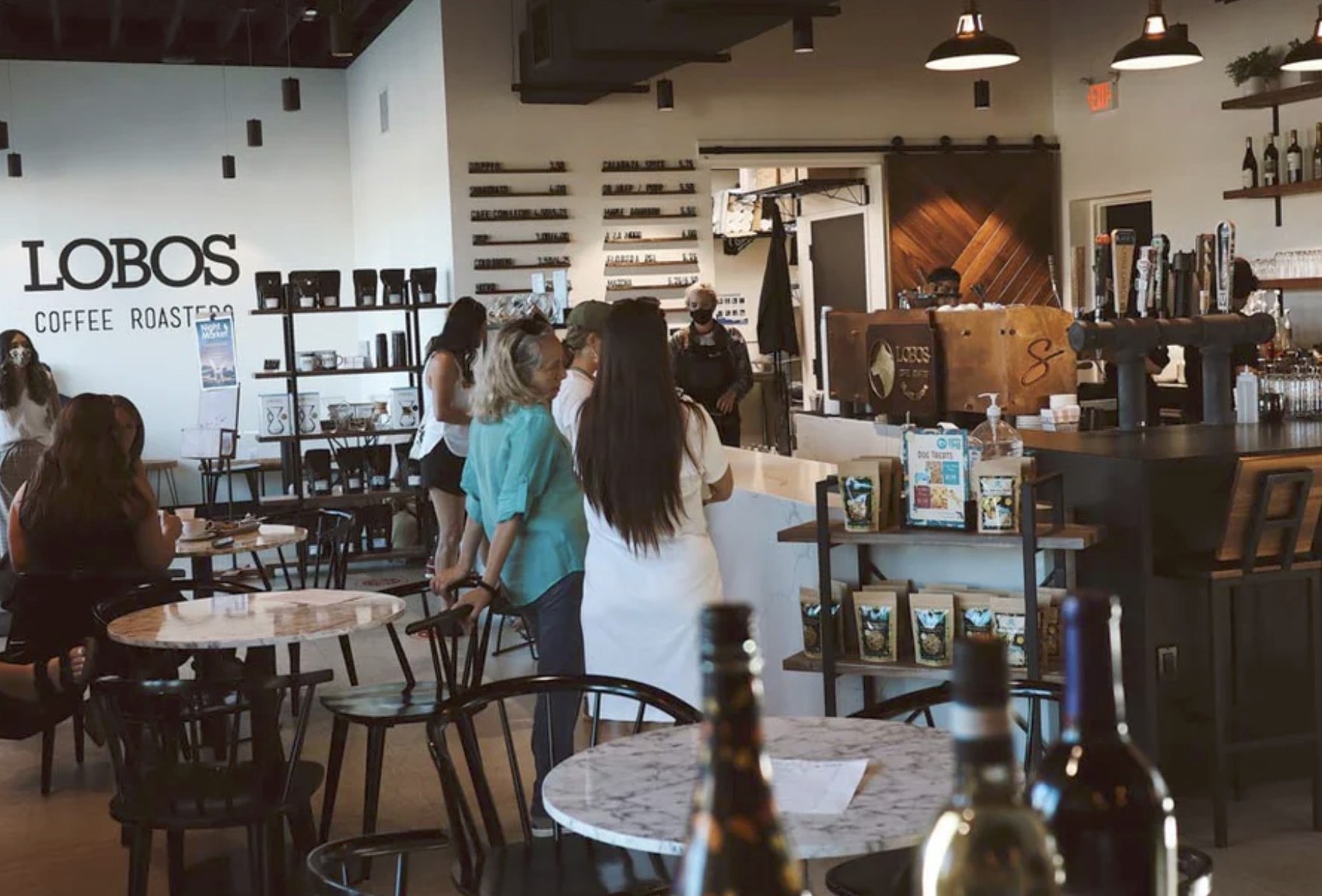 The interior at Lobos Coffee Roasters with the wall lettering and custom wood espresso bar