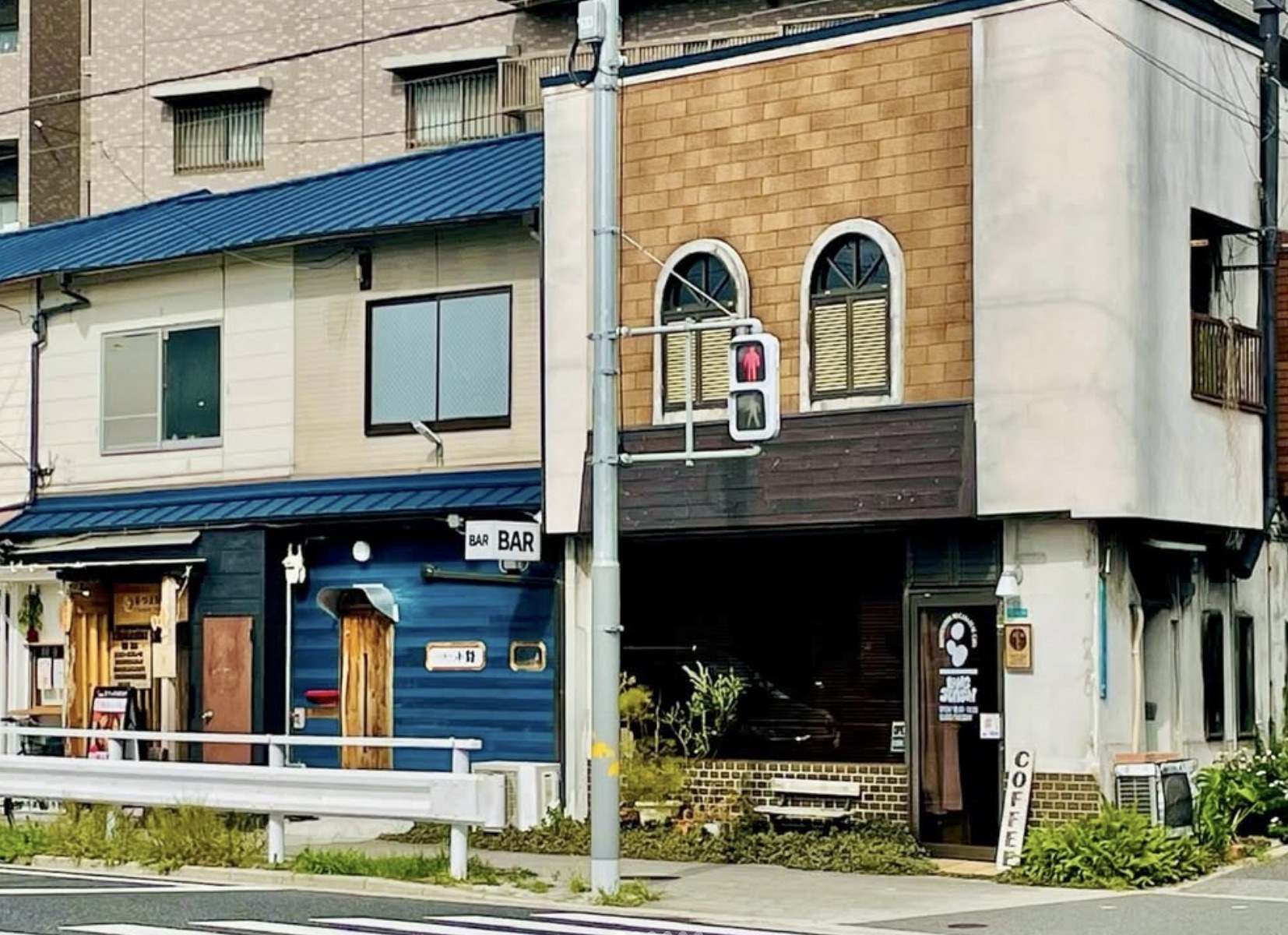 The corner storefront of Coffee Long Season with a vertical COFFEE sign and a dark entrance beside a pedestrian traffic light