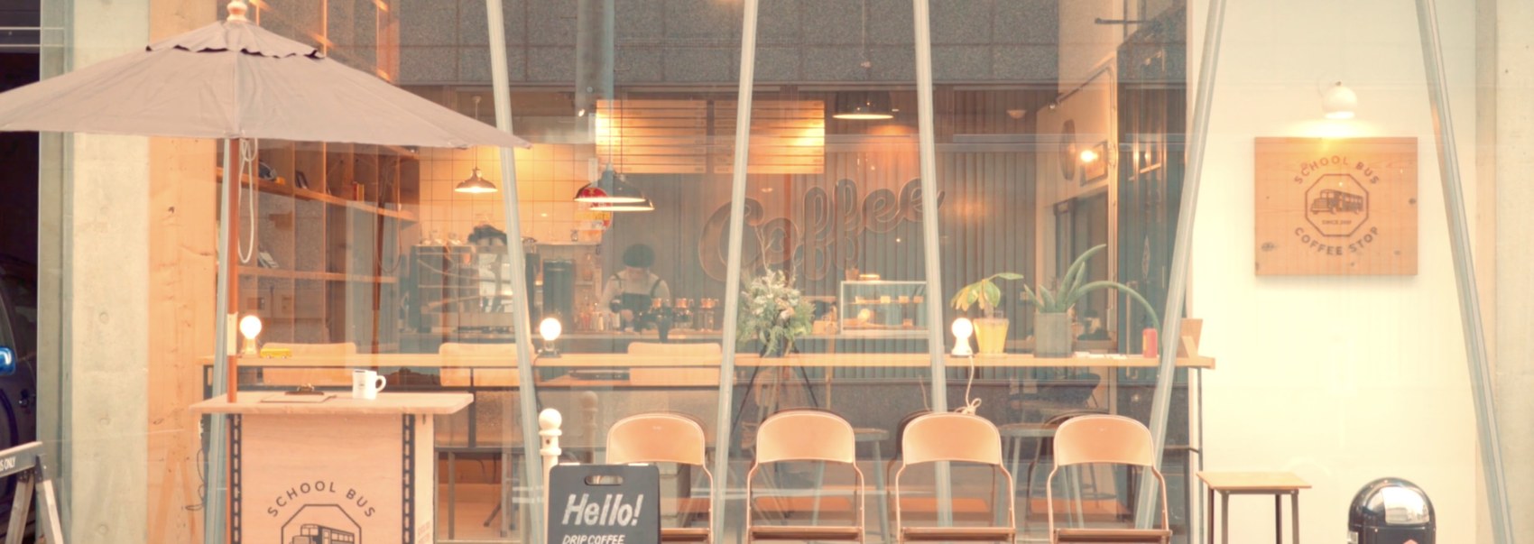 The School Bus Coffee Stop storefront with a large umbrella, folding chairs and a Hello drip coffee chalkboard sign out front