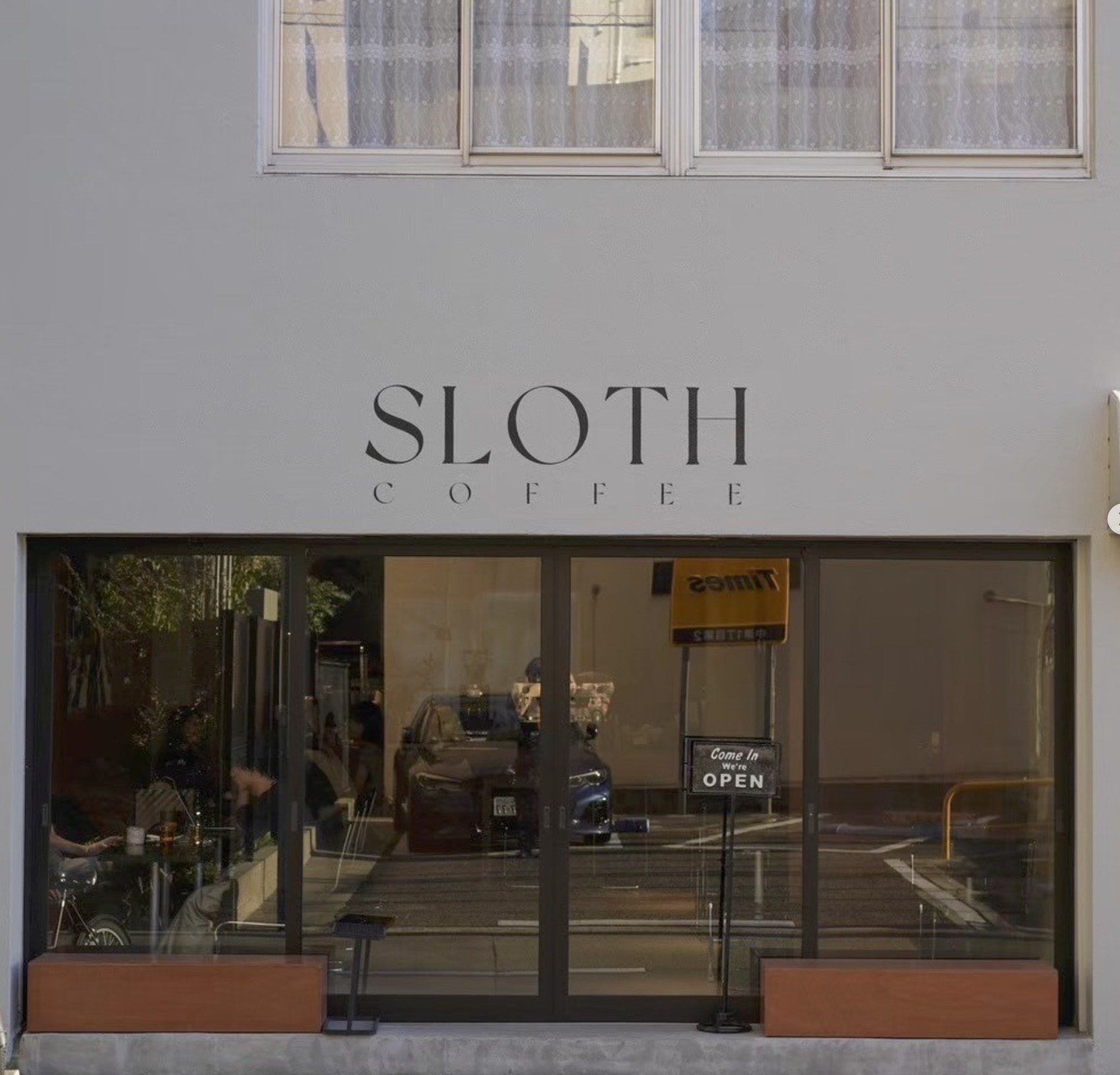 The Sloth Coffee storefront with the shop name lettered above large glass windows and a Come In We're Open sign
